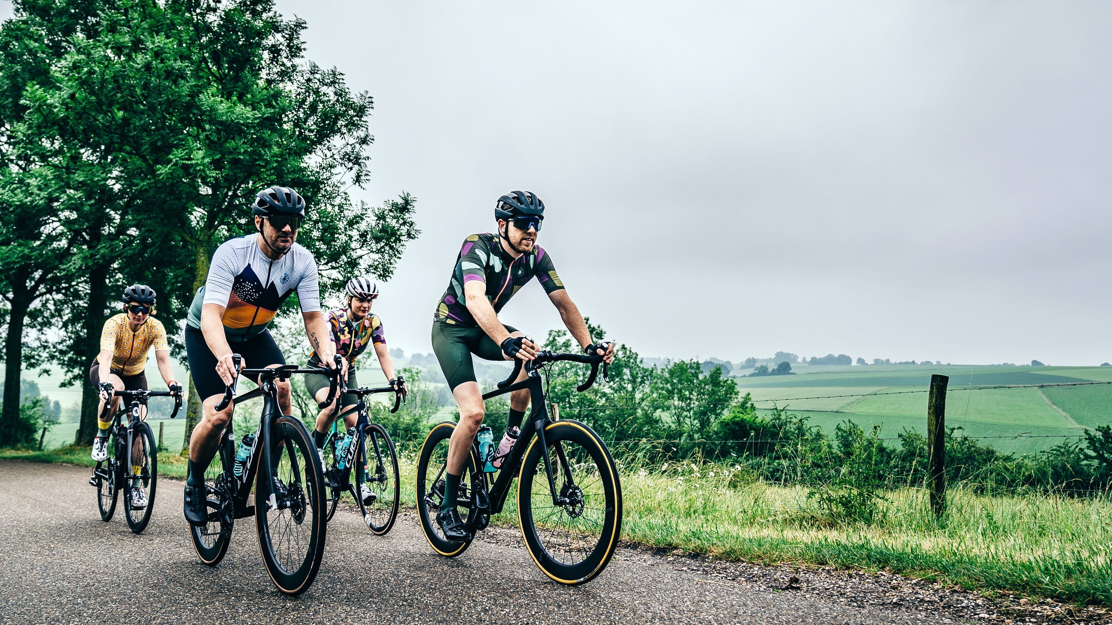 Four cyclists riding on a road with a scenic background