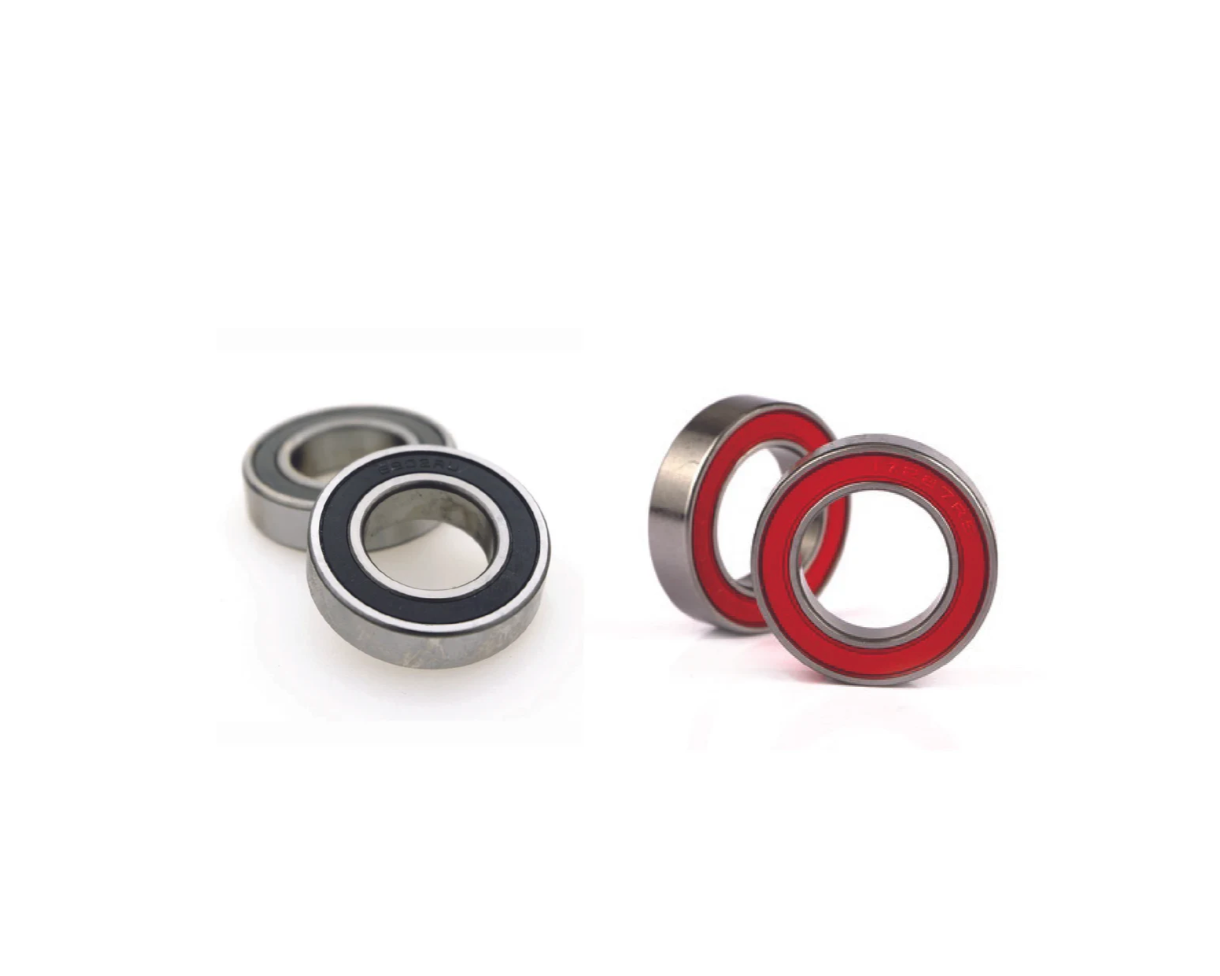Two metal bearings, one with red inner raceway, on a white background