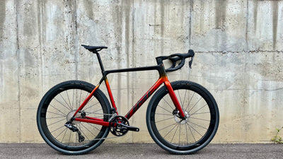 Red and black bicycle leaning against a concrete wall