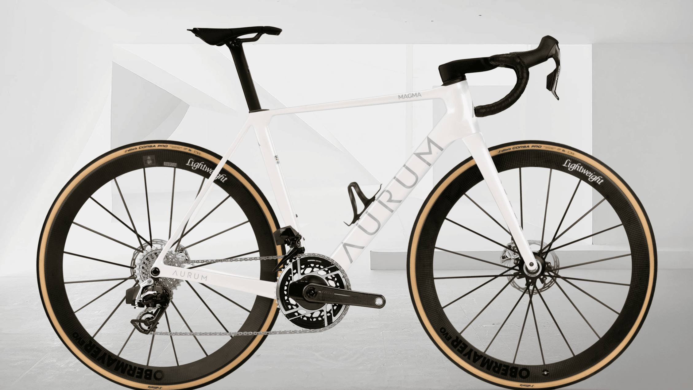 Hvit AURUM Magma landeveissykkel med svarte komponenter og Lightweight Obermayer-hjul, fotografert fra siden mot en lys, minimalistisk bakgrunn.